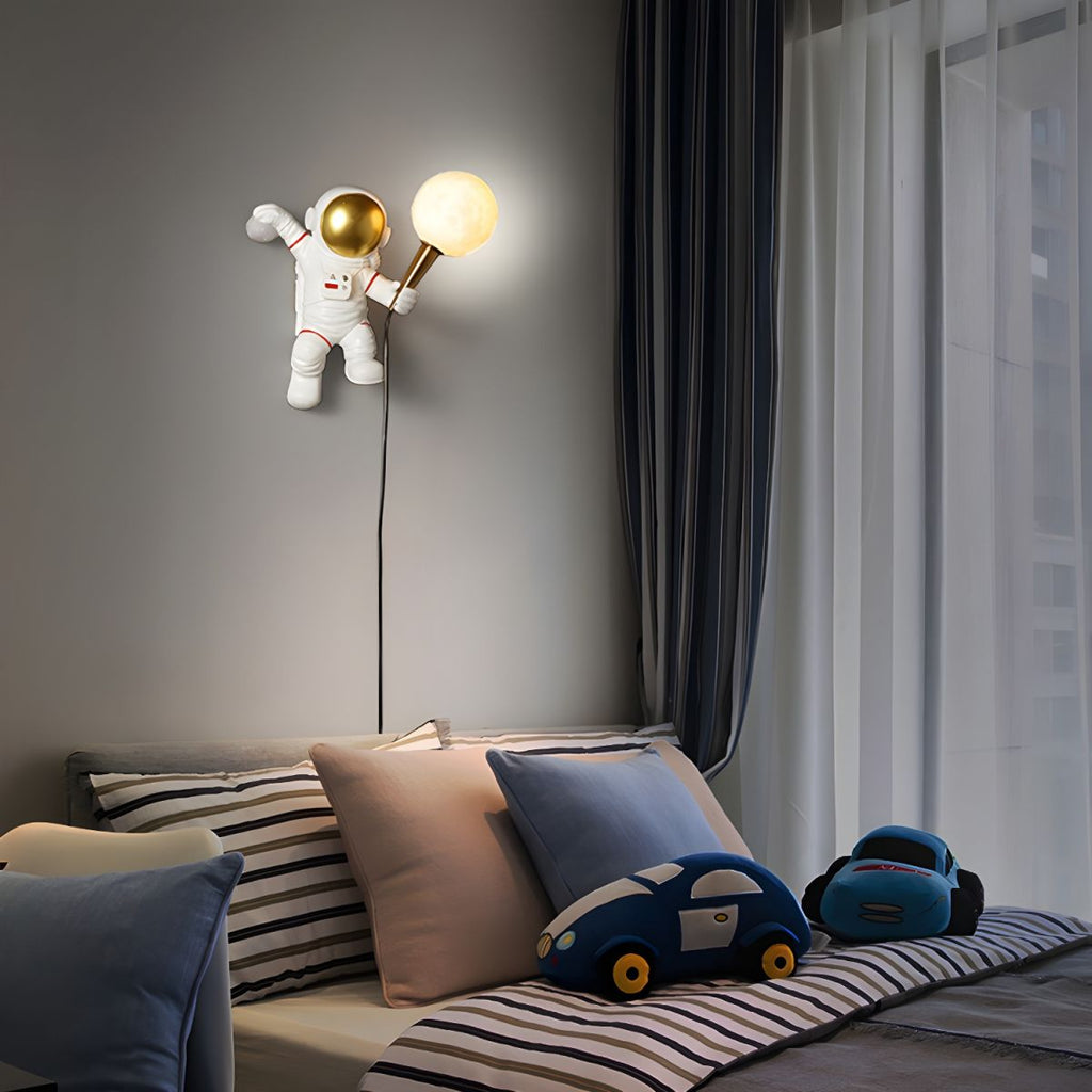 White astronaut wall light with golden moon globe LED bulb mounted above striped bedding in modern kids bedroom setting