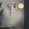 Astronaut wall light with warm white LED moon globe illuminated, mounted on grey wall in modern UK kids bedroom setting