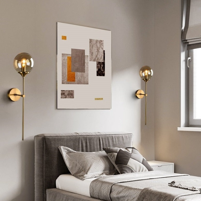 Sizzle brass wall lights with amber glass globes flanking grey upholstered bed in modern UK bedroom interior